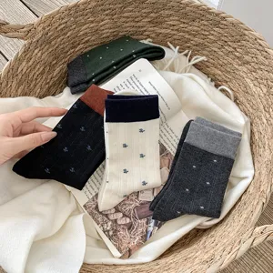 Detail shot of cozy women's wool mid-tube socks featuring contrast color cuffs and cute floral patterns.