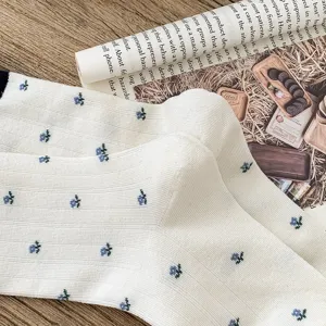 Close-up detail of white mid-calf socks with blue floral pattern and contrast cuff.