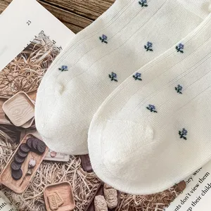 Women white mid-tube socks featuring delicate blue floral embroidery, soft and breathable daily wear.