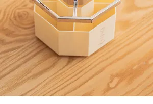 Macro detail of rotating cosmetic organizer with metallic trim on wooden surface