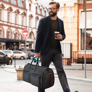 Professional man carrying a large black multifunctional travel duffel bag on a city street