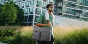 Hombre con un gran maletín gris para portátil en un entorno de parque urbano