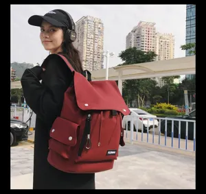 Large red waterproof student backpack with high capacity being worn by a young woman outdoors