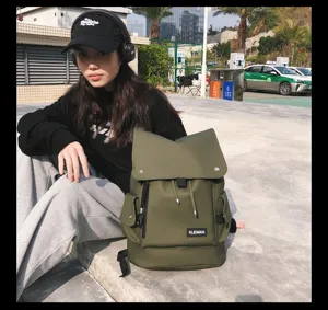 Outdoor lifestyle shot of an olive green waterproof backpack with a large top flap.