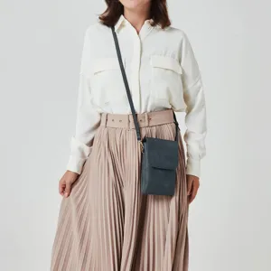 Detailed view of the dark blue PU leather phone bag styled with a pleated skirt.