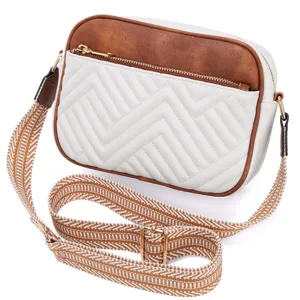Close-up view of a white chevron quilted crossbody bag featuring a wide patterned strap
