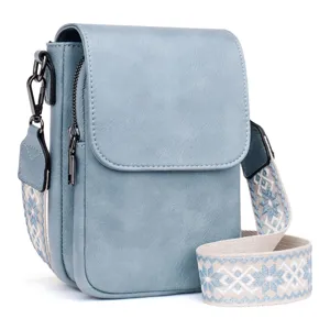 Detalle de bolso bandolera de PU azul claro con correa étnica y cremallera lateral
