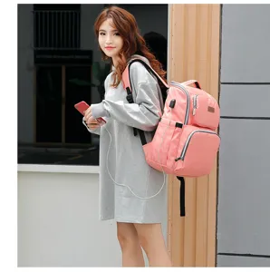 Modelo asiática con mochila pañalera rosa multifuncional con puerto de carga USB