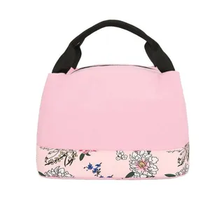 Gros plan détaillé du sac à lunch rose avec motif floral sur le fond et poignées noires.