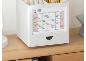 Close-up of a white rotatable 2027 desk calendar and desktop stationery organizer box