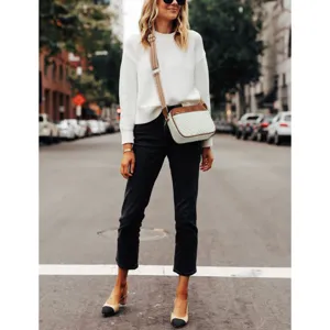 Elegant white quilted crossbody bag with brown trim shown in a stylish urban street setting