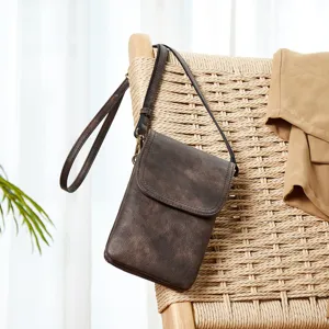 Detailed shot of a vintage-style brown PU leather crossbody phone bag on a woven chair