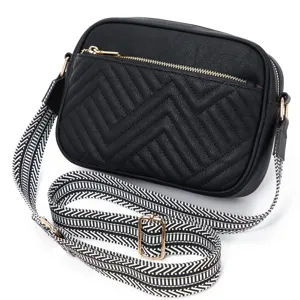 Detailed view of black quilted crossbody bag featuring a stylish patterned wide strap.