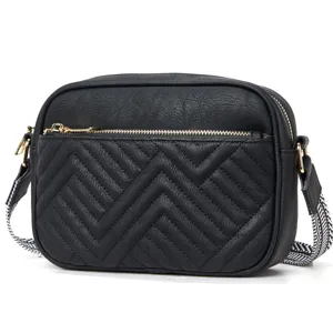Detail view of black retro crossbody bag with chevron quilting and patterned strap.