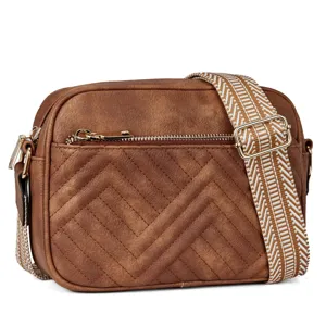 Detailed view of brown faux leather crossbody bag with chevron quilting and wide strap.