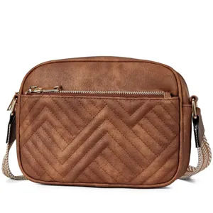 Close-up of brown quilted crossbody bag with chevron pattern and gold zipper.