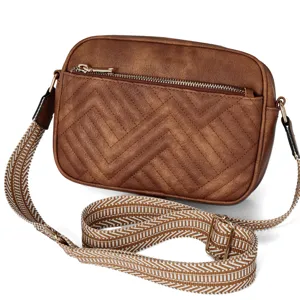 Detail view of a vintage brown quilted crossbody bag with a wide patterned strap.