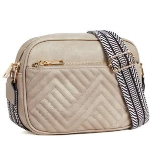 Detail of beige quilted crossbody bag featuring a stylish patterned wide strap