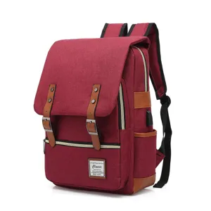 Detail of a vintage burgundy canvas laptop backpack with USB port and leather straps