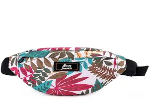 Detail view of a colorful tropical leaf print travel fanny pack with a black logo patch