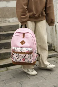 Vue de détail extérieure d'un sac à dos décontracté en toile rose avec poche florale.