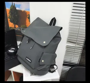 Close-up of dark grey waterproof laptop backpack with KLEIMAN brand label on white desk.