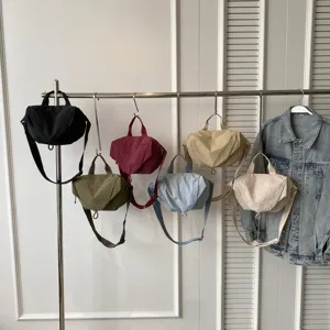 Variety of nylon dumpling crossbody bags in different colors hanging on a display rack.