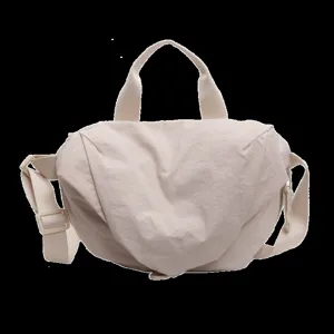 Detailed view of beige nylon dumpling crossbody bag with adjustable strap for sports