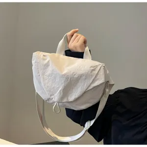 Detailed view of an off-white nylon dumpling crossbody bag with adjustable strap.