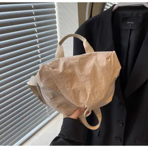 Detailed view of a stylish beige nylon dumpling crossbody bag held in a hand context