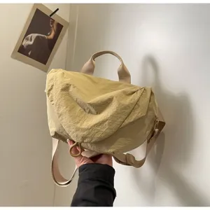 Close-up of a light yellow nylon dumpling crossbody bag featuring a crinkled texture