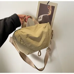 Detailed view of a beige nylon dumpling crossbody bag with adjustable strap