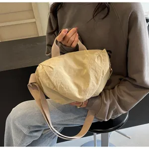 Detailed shot of beige nylon dumpling crossbody bag with adjustable strap on model