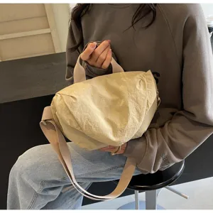 Detail view of a beige nylon crescent crossbody dumpling bag with adjustable strap