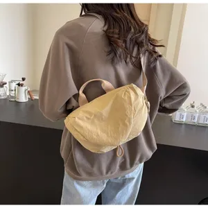 Detail of a beige nylon dumpling crossbody bag worn by a model in a casual setting
