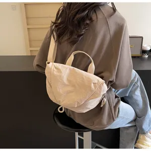Back view of a model wearing a beige nylon dumpling crossbody bag with magnetic closure
