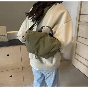 Model wearing a green nylon dumpling crossbody bag in a minimalist lifestyle setting