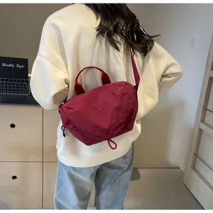 Back view of a stylish burgundy nylon dumpling bag worn as a crossbody for sports and cycling