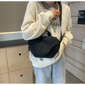 Detail view of a black nylon dumpling crossbody bag styled on a casual model outfit.