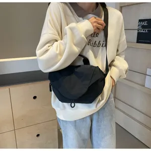 Close-up of a model wearing a black nylon dumpling crossbody bag with adjustable strap
