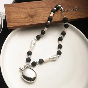 Detailed view of a silver pebble pendant necklace with black beads and pearls.
