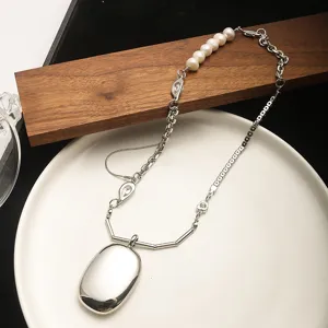 Close-up of minimalist silver-tone necklace with pearls and oval pendant detail