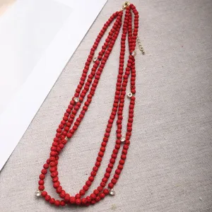 Vista detallada de un collar de suéter de piedra de lava roja con pequeños dijes de corazón