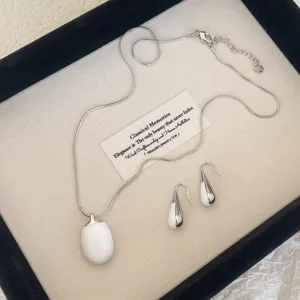 Detailed view of minimalist white enamel and silver-toned necklace and earrings set