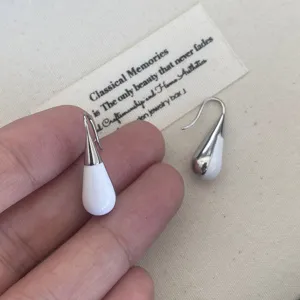 Detailed view of white enamel teardrop earrings with elegant silver metal plating