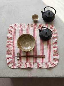 Red and white striped ruffled placemat on a minimalist concrete table setting detail