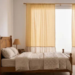 Detail von gelben Gingham-Vorhängen mit Rüschensaum aus Leinen im gemütlichen Schlafzimmer