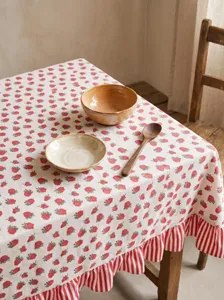 Macro view of pastoral cotton linen tablecloth with red floral pattern and ruffled edges.