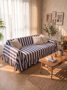 Blue and white striped velvet sofa cover with ruffled hem in a cozy living room.