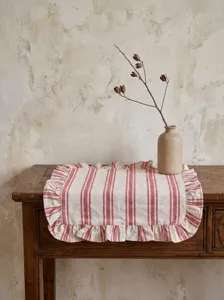 Vintage red and white striped ruffled placemat on a rustic wooden table detail view